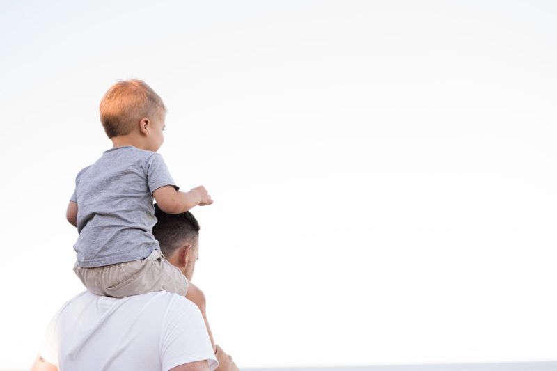 Child on Father Shoulder Raising a Happy Child
